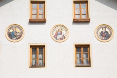 Fassade Peter-Anich-Haus mit Porträts von Peter Anich, Blasius Hueber und Christus